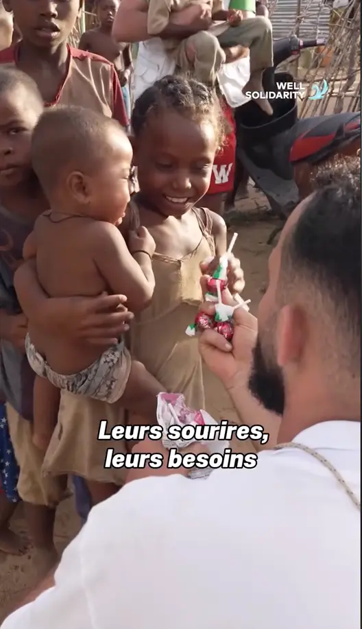 Homme distribue des bonbons à des enfants souriants.